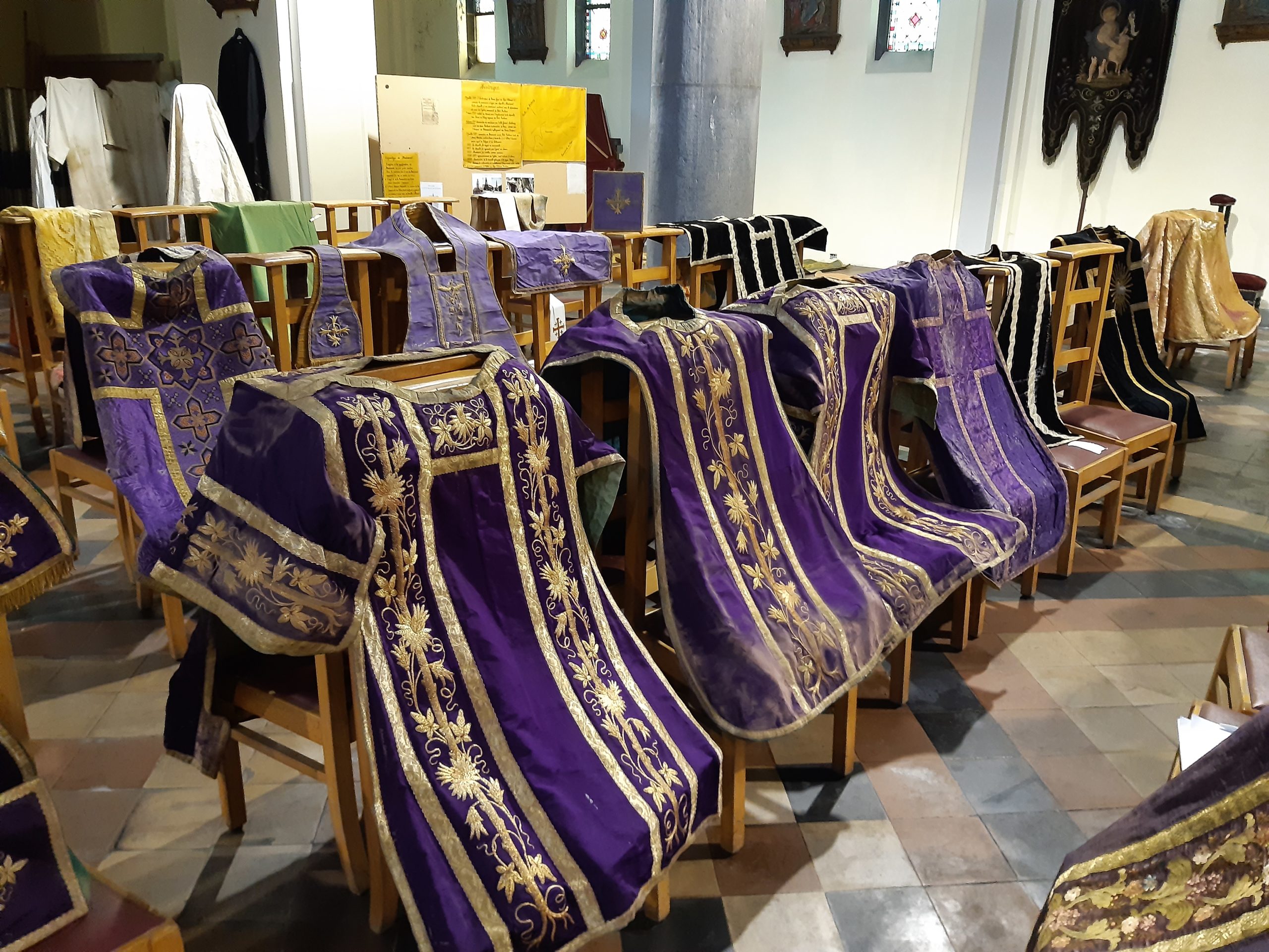 Chasubles et dalmatiques mises à sécher sur les chaises d’églises. Les cartons d’empesage contenu dans ces vêtements ont désormais adopté la forme des chaises…©Corinne Van Hauwermeiren